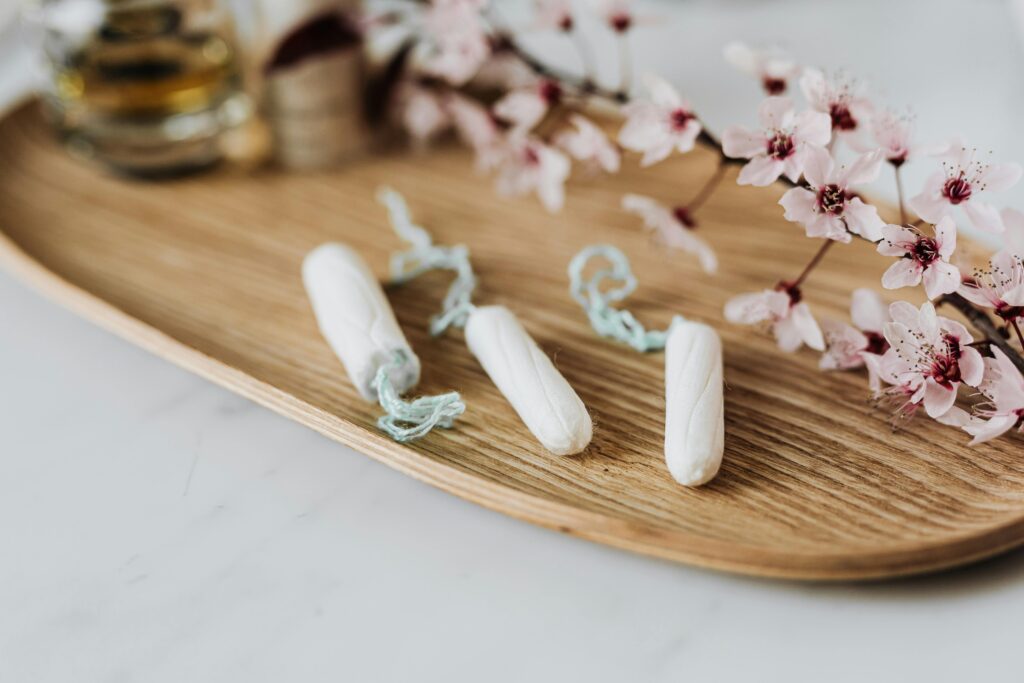 three tampons on a wooden tray next to a decorative branch of cherry blossom flowers